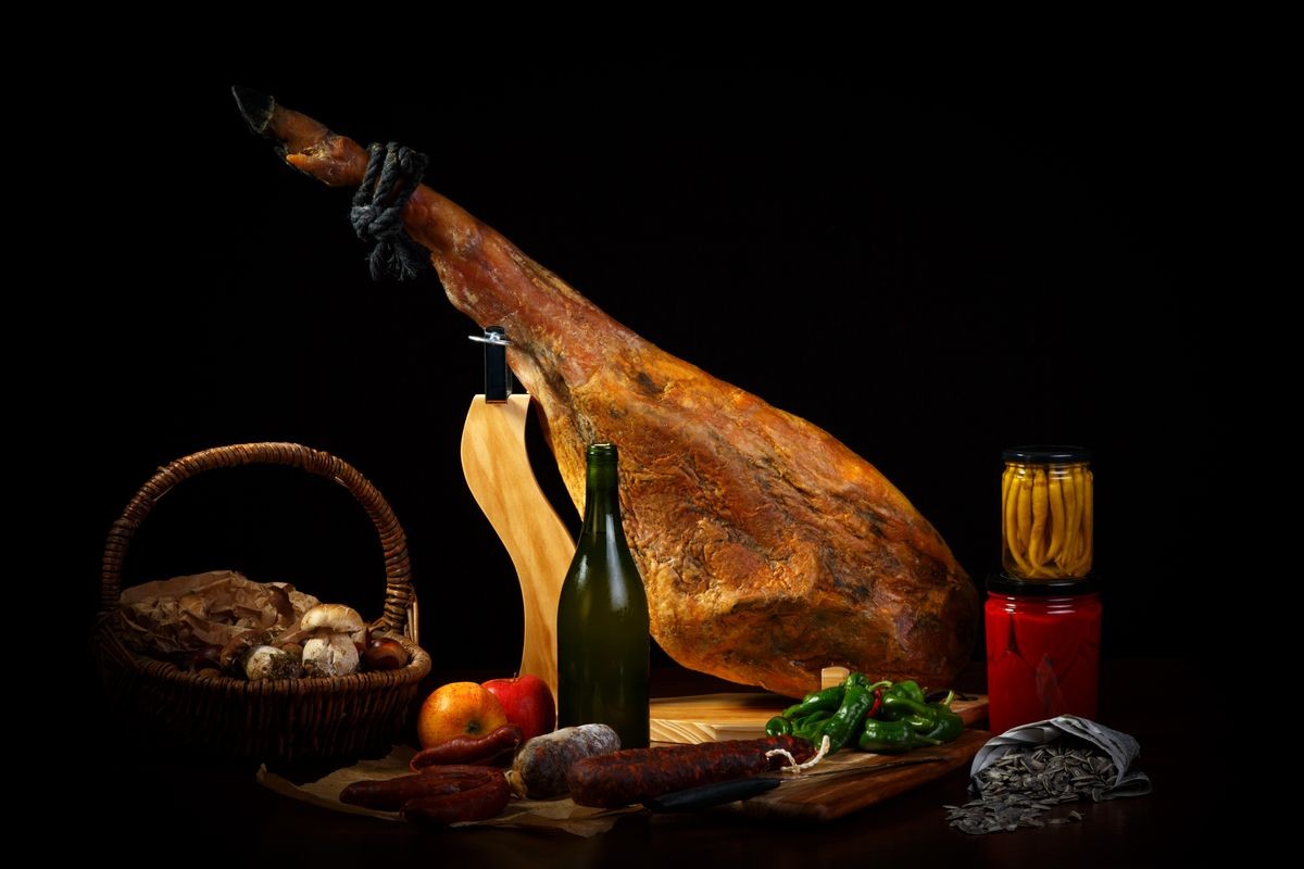 Hamon is forty-eight weeks old with wine, seeds and peppers on the table. Still life with a Spanish jamon and traditional food.Food art in a low key. A selection of gastronomic products of Spain